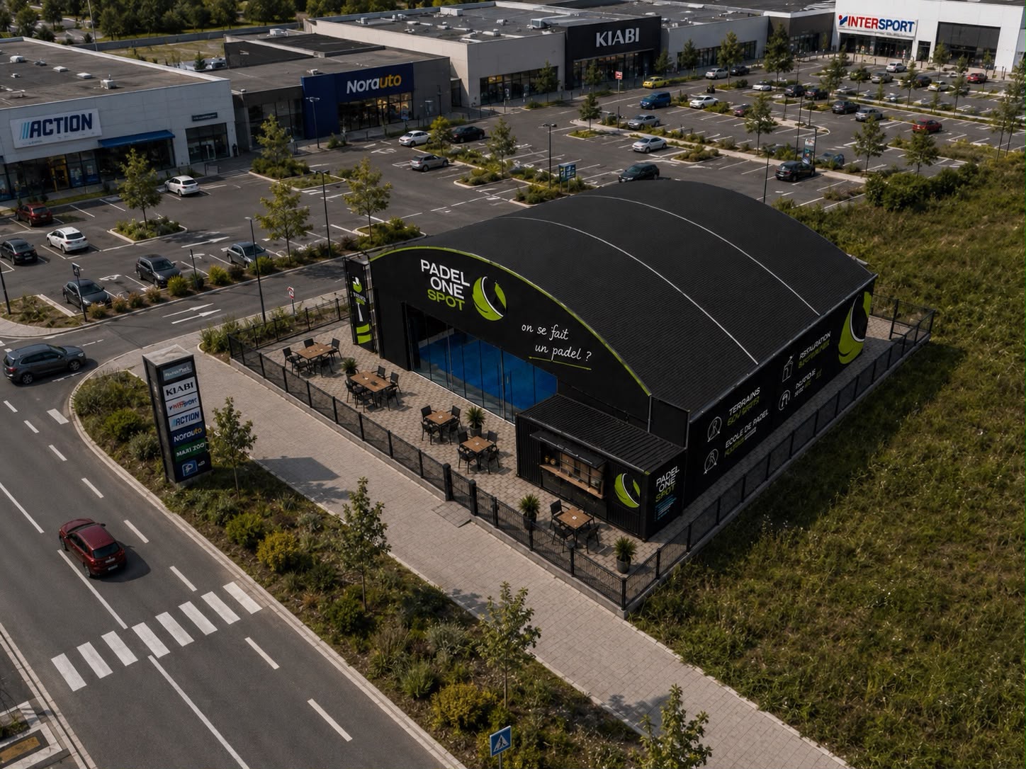 Padel One Spot implante au coeur d'une zone commerciale avec parking, enseignes et flux visibles